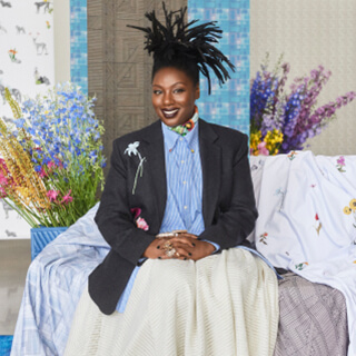 A portrait of the designer Mimi Plange with her collection of window treatment materials for The Shade Store behind her.