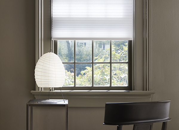 A small office has a desk in front of a window with Cellular Shade made of 3/4 Single Cell Light Filtering material in Lace