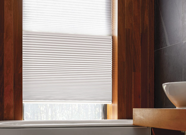 A bathroom with wood walls has a Day Night Cellular Shade made of Single-Cell Blackout and light filtering material in White