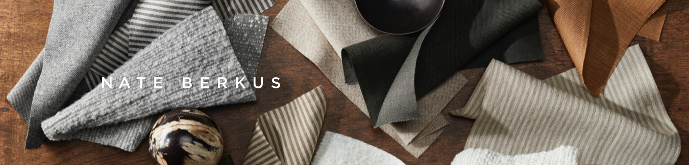 Wood table top featuring Nate Berkus logo with fabric swatches in various neutral shades of grey and tan