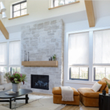 A beautiful open living room with a modern organic aesthetic, features Flat Roman Shades made of Sheer Wool Blend in Cloud.