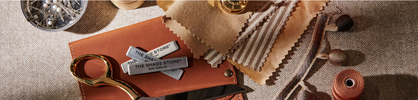 Fabric swatches from the Nate Berkus Collection and trim from the Samuel & Sons sit with scissors and thread on a table