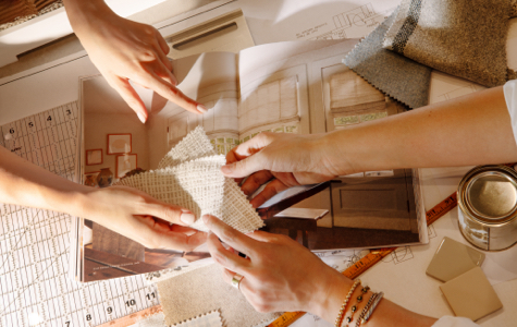 A table top stacked with materials and The Shade Store's Big Book opened under hands during a design consultation