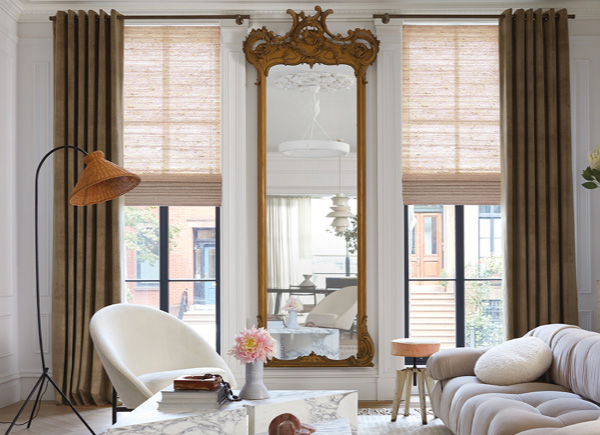 Two long windows featuring grommet drapery in velvet camel in a living room with white seating and a long gold framed mirror
