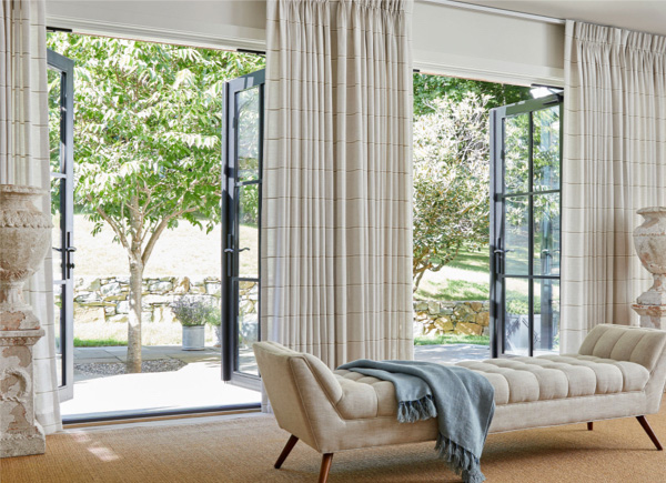 Open patio doors featuring pinch pleat drapery in sankaty stripe sand in a room with a long white chaise and large vases